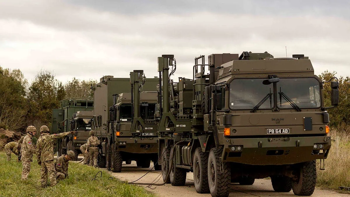 British Army personnel operating military trucks equipped with communication systems and fibre optic cabling during field deployment.