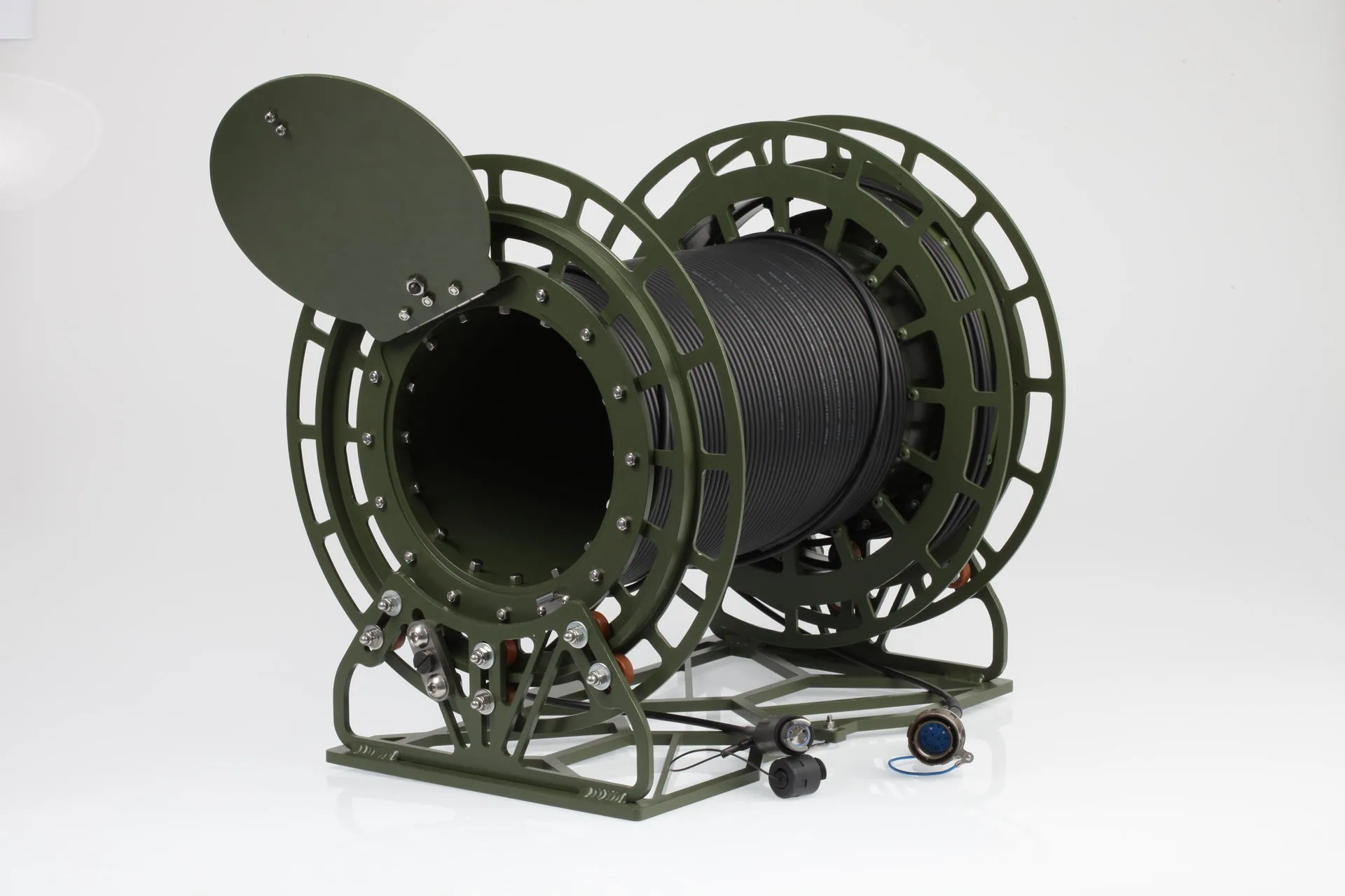 A detailed product shot of a large, olive-green military-grade cable dispenser with a central reel of thick, black cable. The hinged side cover is open, and the entire unit rests on a sturdy metal frame.
